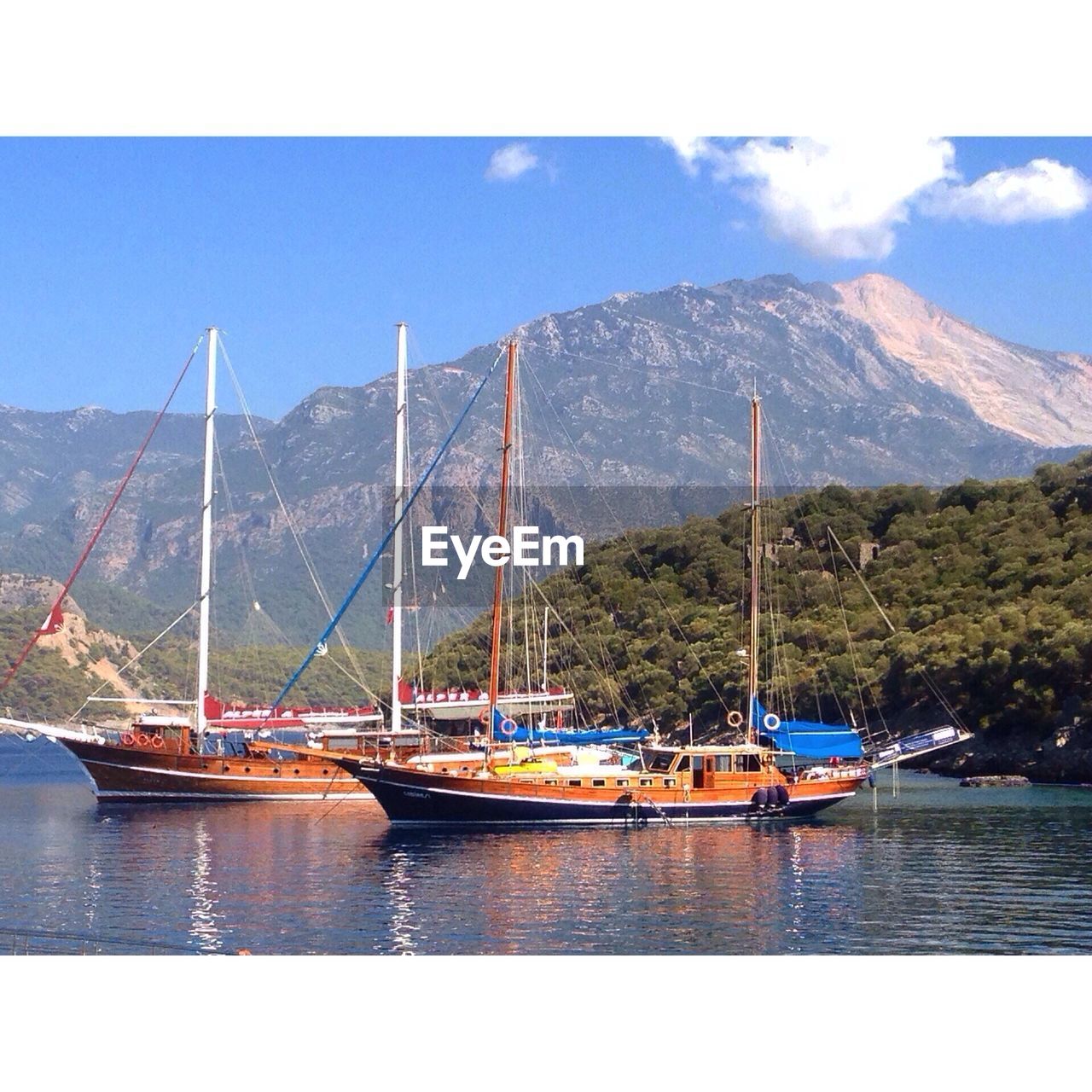 Nautical vessels moored on lake against mountain