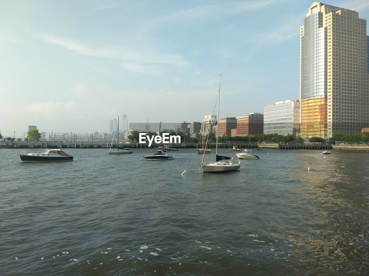 Sailboats in sea against modern buildings in city