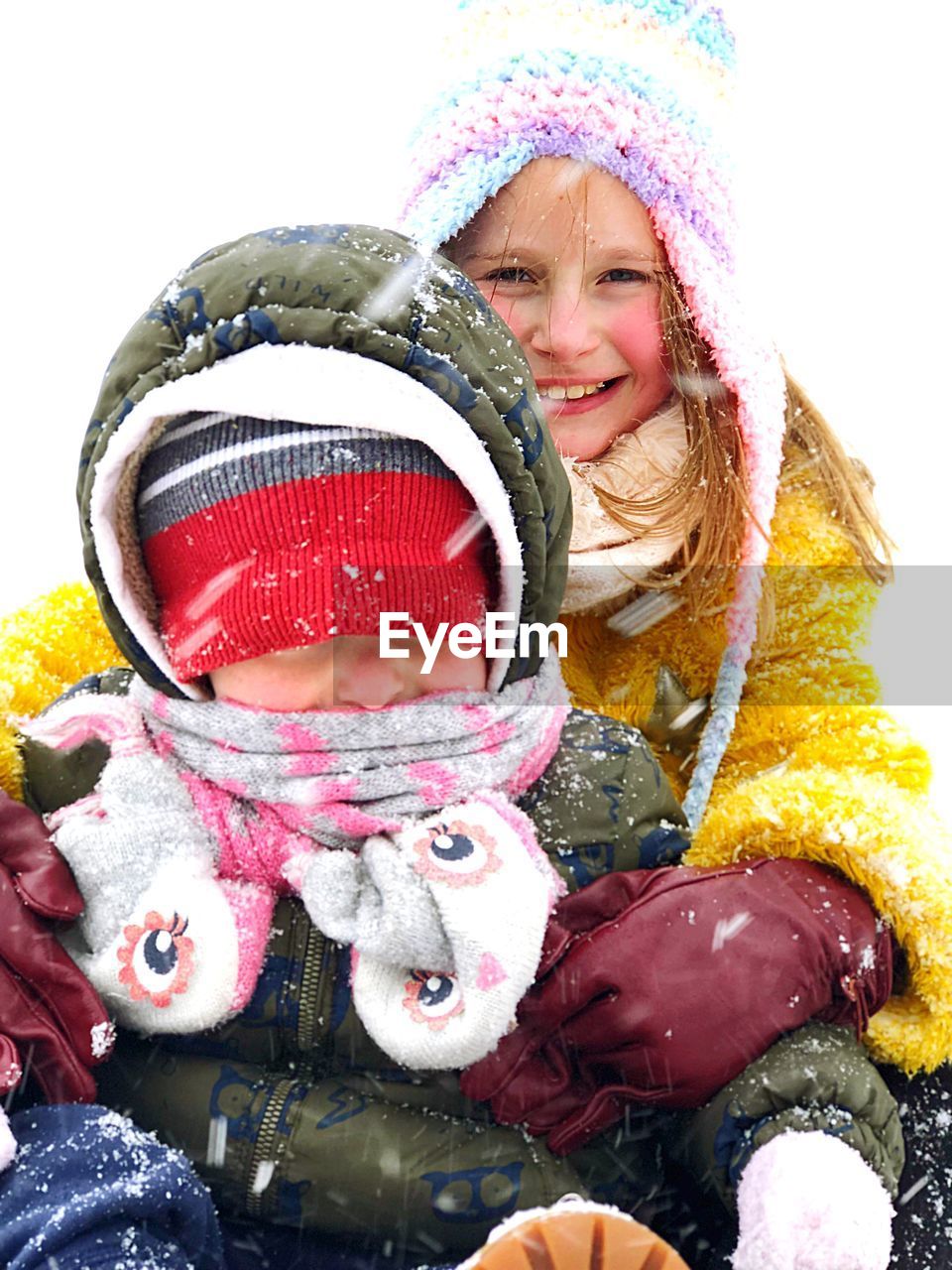 Portrait of smiling girl with brother during snowfall