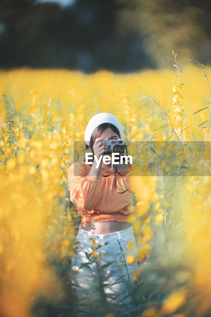 Young woman photographing on field