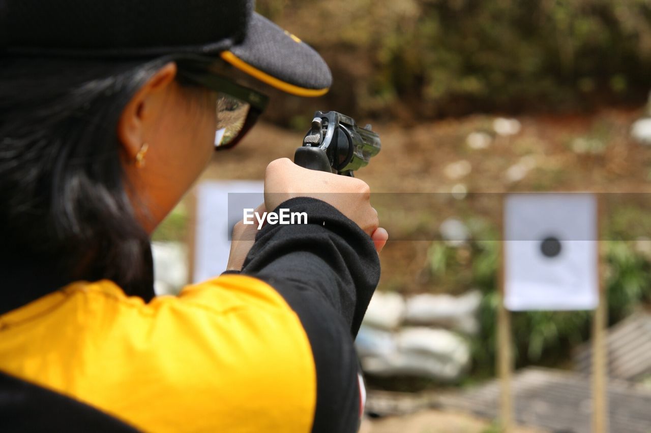 Cropped image of woman practicing target shooting with gun