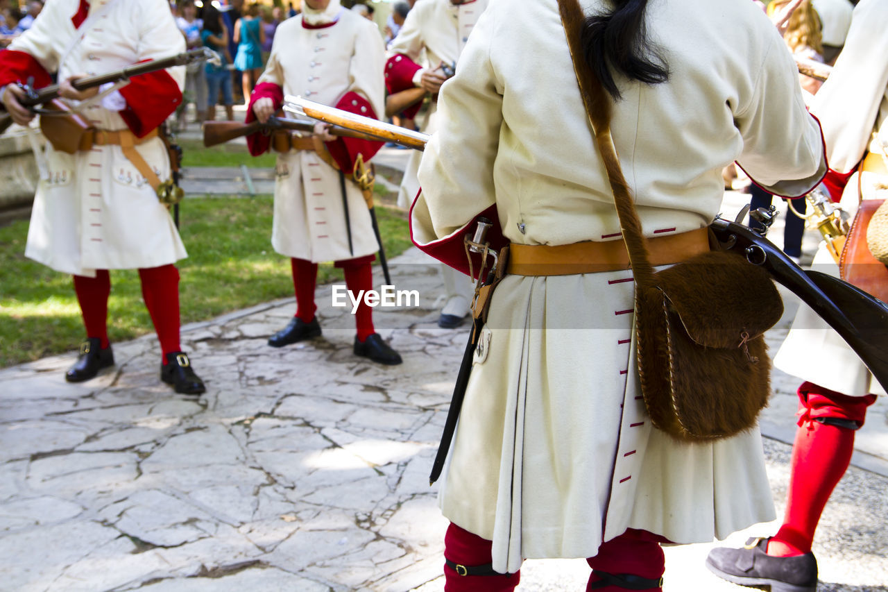 People in costume with weapons standing on footpath