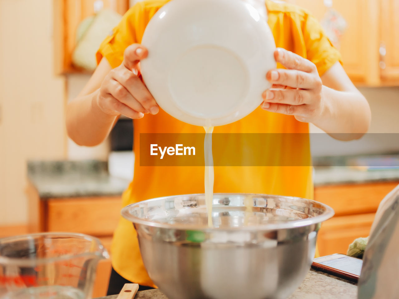 Midsection of woman pouring butter in pan