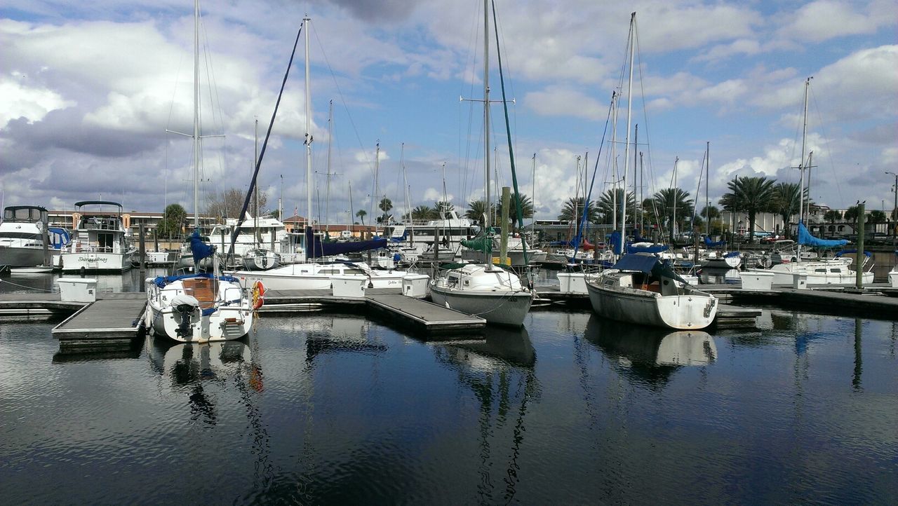 Boats moored in lake against cloudy sky