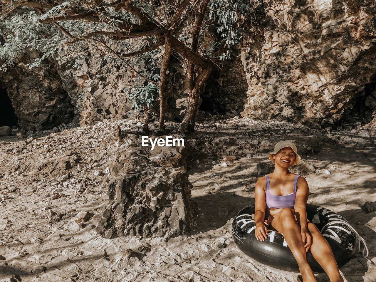 Full length of woman sitting on inflatable ring over mud