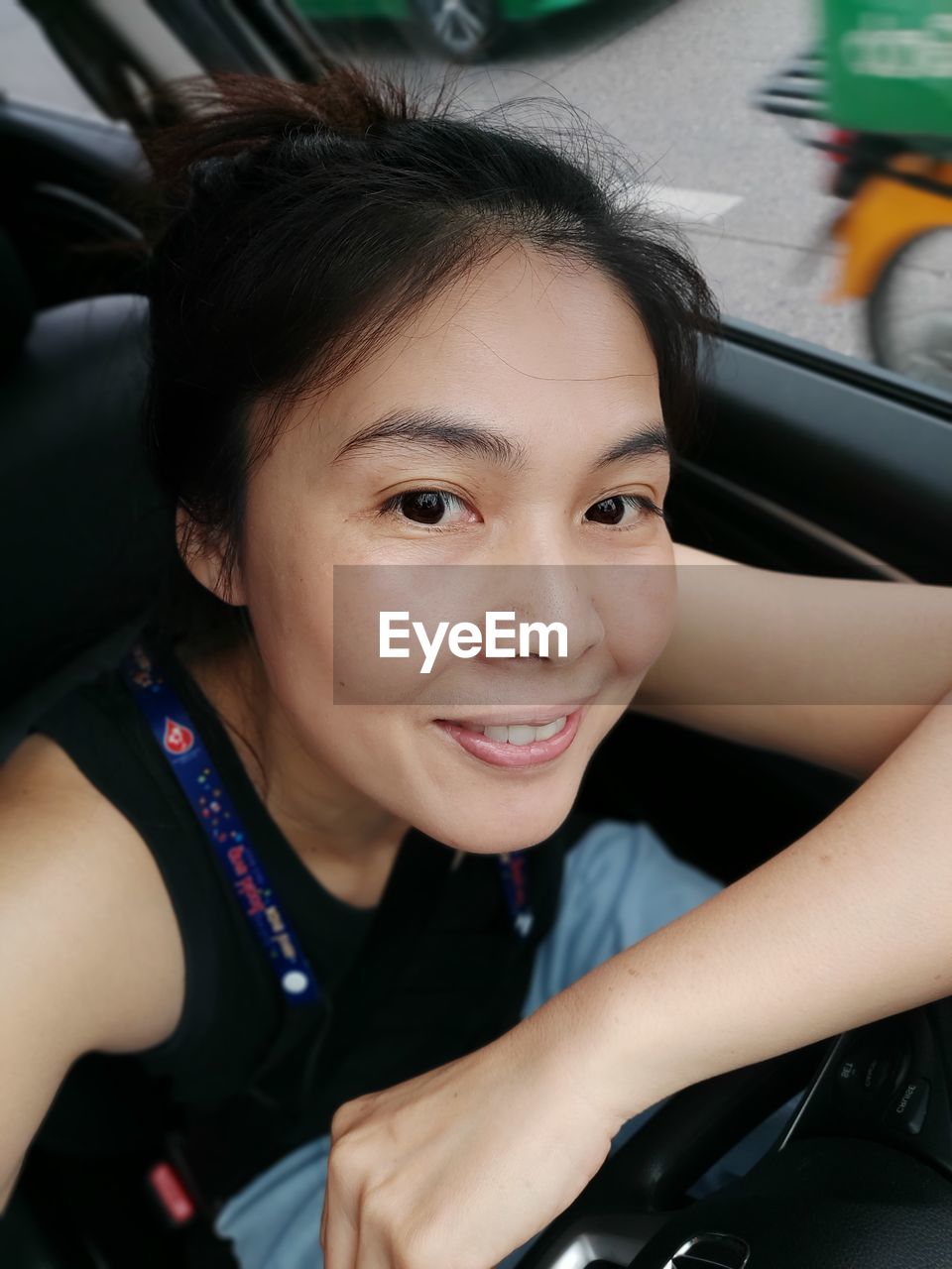 PORTRAIT OF SMILING YOUNG WOMAN IN CAR