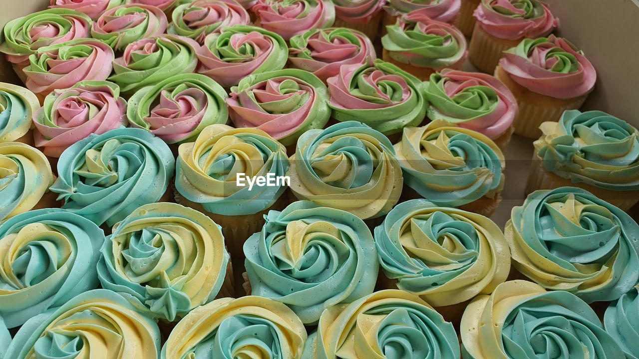 flower, cake, icing, dessert, food, large group of objects, cupcake, freshness, multi colored, no people, abundance, cake decorating, high angle view, food and drink, indoors, full frame, in a row, plant, beauty in nature, sweet food, close-up, still life, arrangement, sugar paste