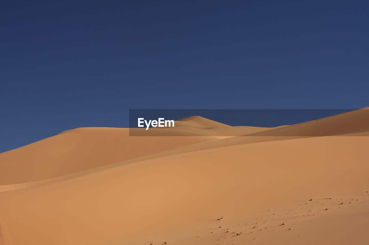 Scenic view of sahara desert against clear blue sky, libya