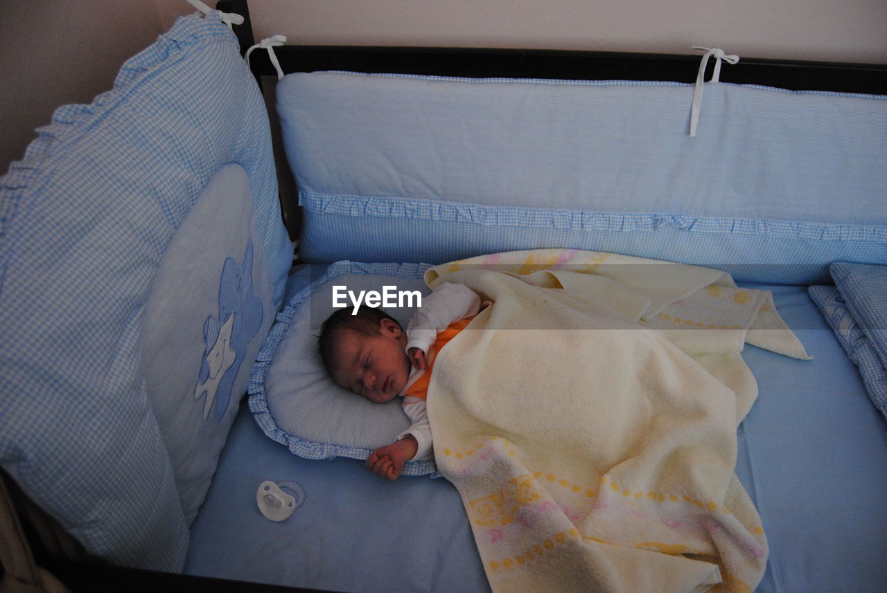 High angle view of child lying in crib