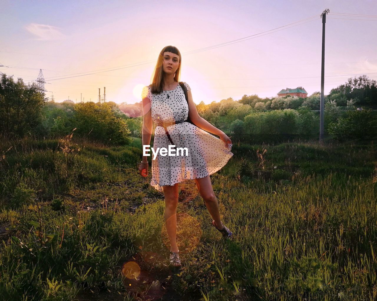 Portrait of woman standing on field against sky during sunset