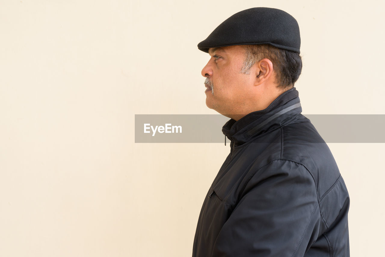 MAN LOOKING AWAY WHILE STANDING AGAINST WALL