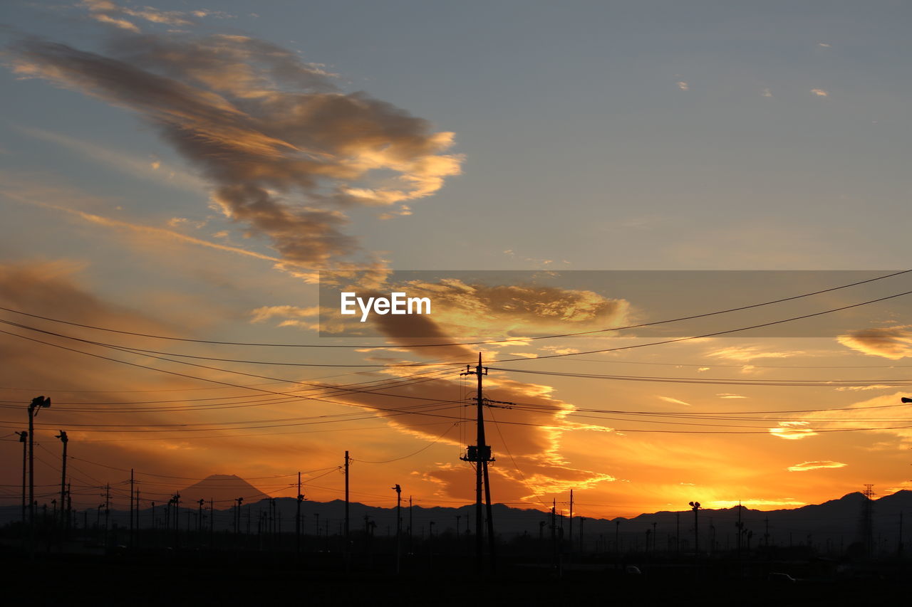 Silhouette power lines against sky during sunset