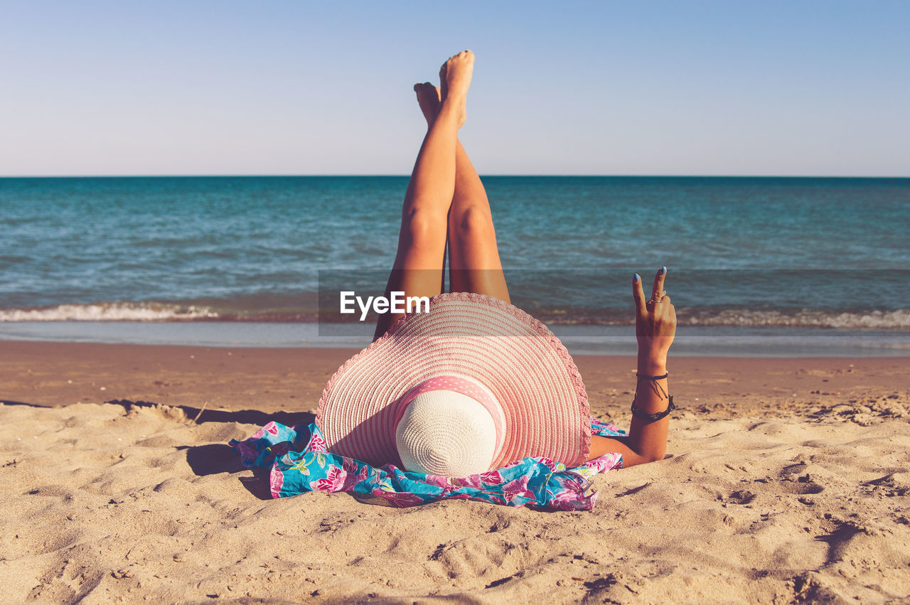 Low angle view of woman lying on beach against sea