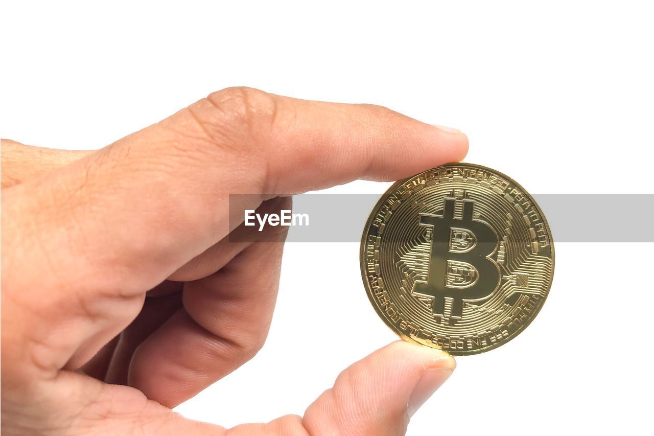 Cropped hand holding bitcoin against white background