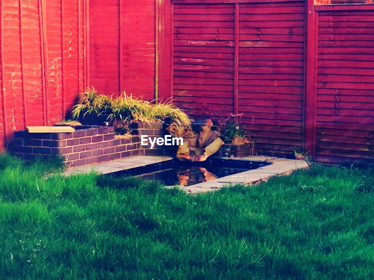 PEOPLE SITTING ON GRASS AGAINST WALL