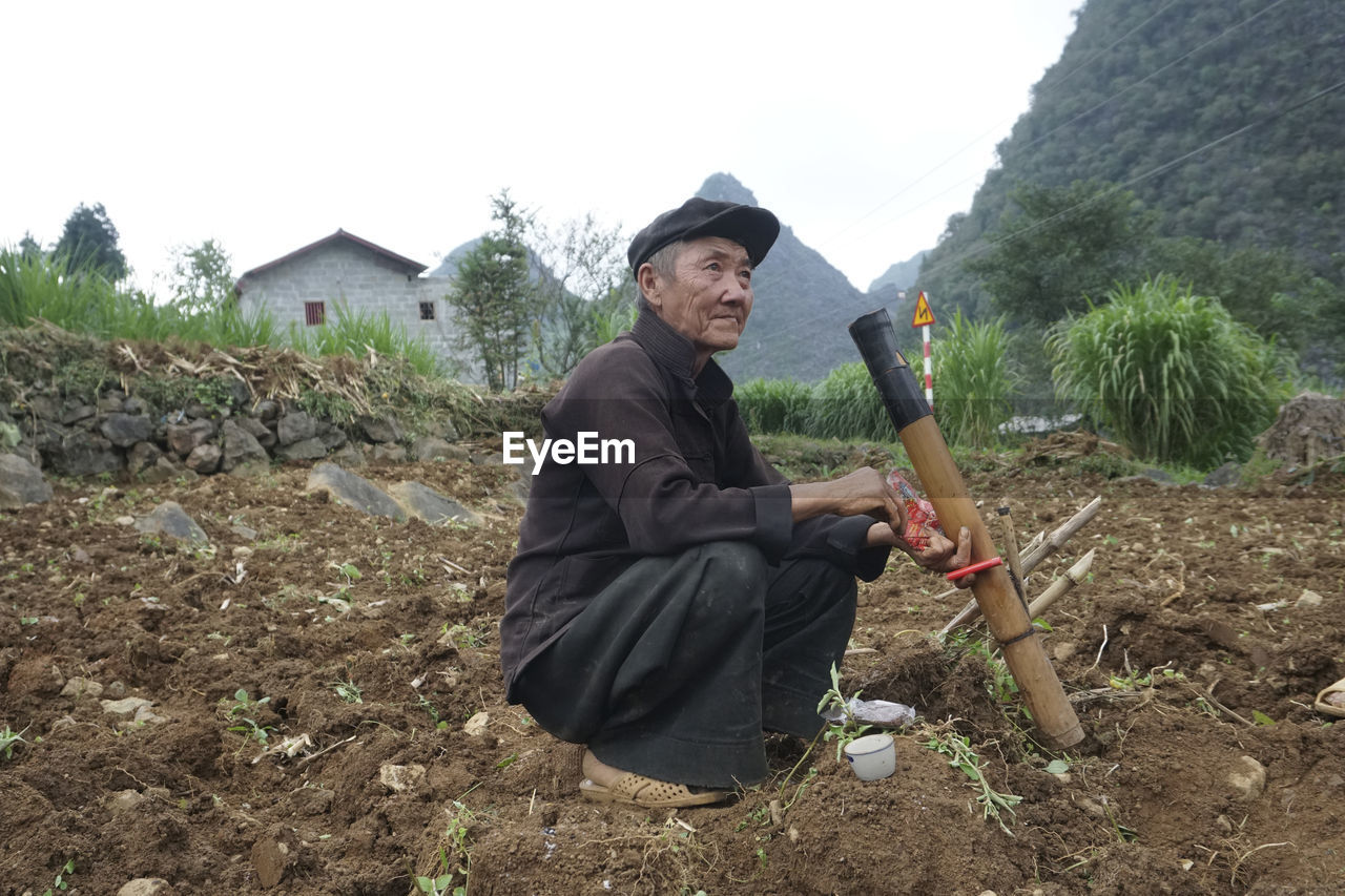 SIDE VIEW OF MAN HOLDING CAMERA ON LAND