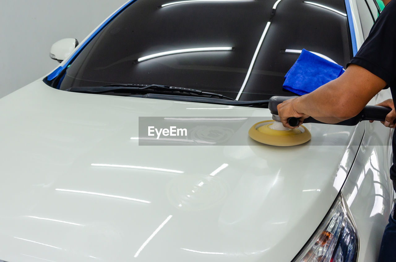 Cropped hands of mechanic polishing car in garage