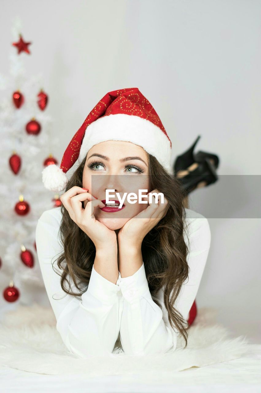 Thoughtful woman wearing santa hat lying on bed