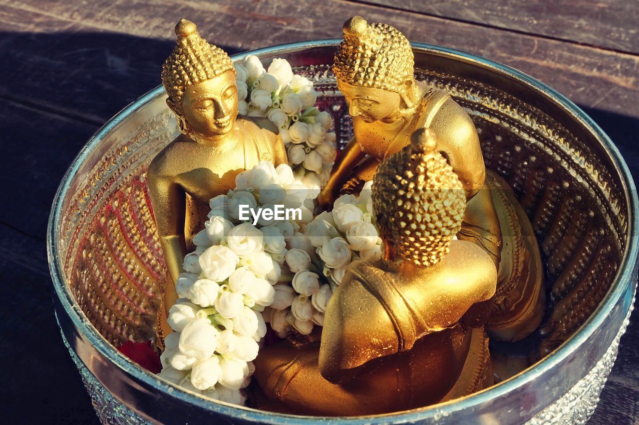 High angle view of buddha statues and floral garland in container