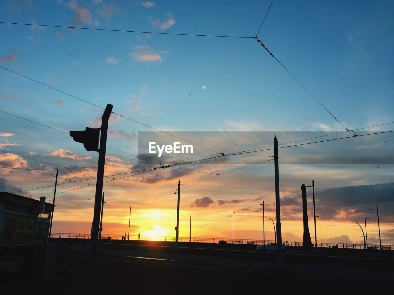 Silhouette built structures against cloudy sky during sunset