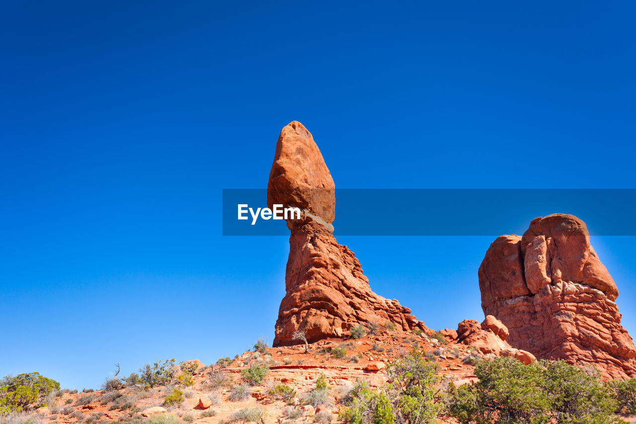 LOW ANGLE VIEW OF ROCKS AGAINST CLEAR BLUE SKY