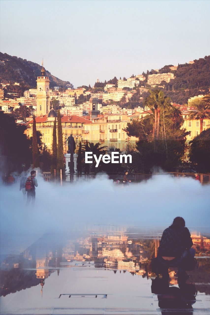 People looking on smoky street against cityscape