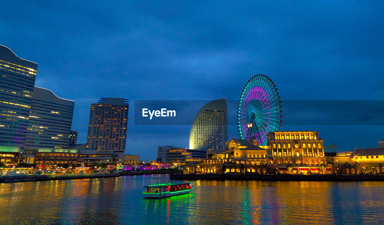 ILLUMINATED CITY BY RIVER AGAINST SKY