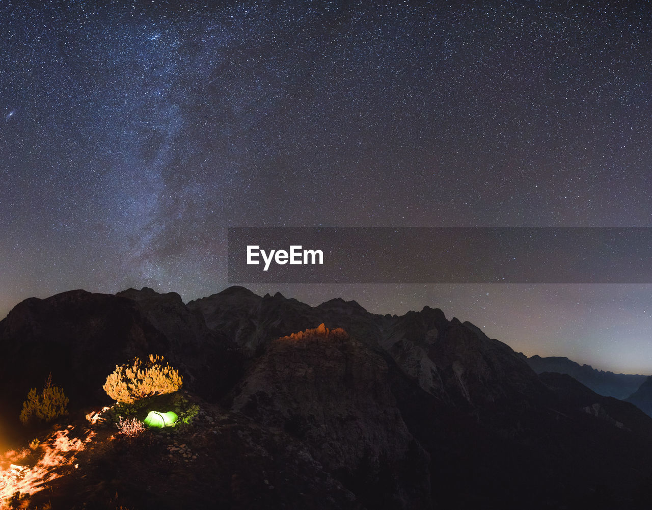 Scenic view of illuminated mountains against sky at night