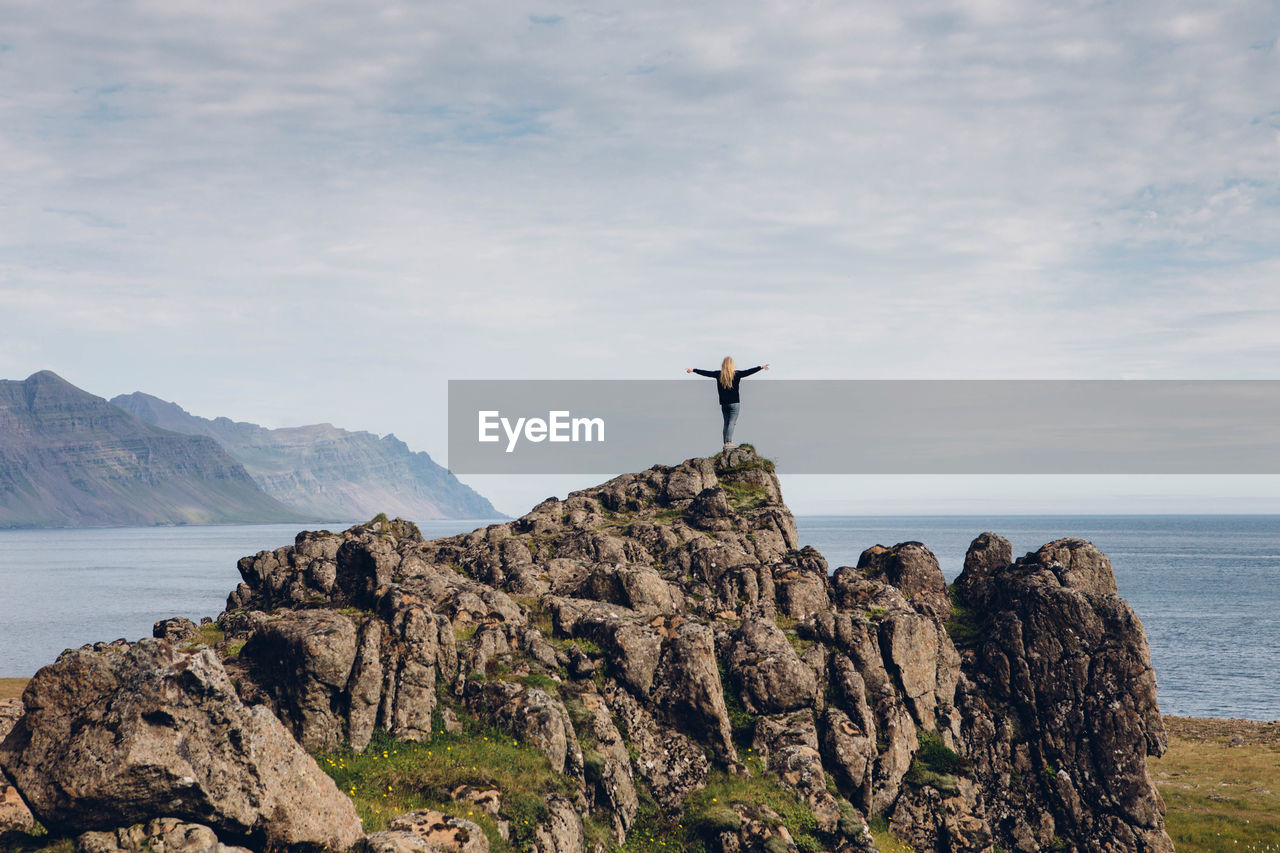 Rear view of woman on rock against sea