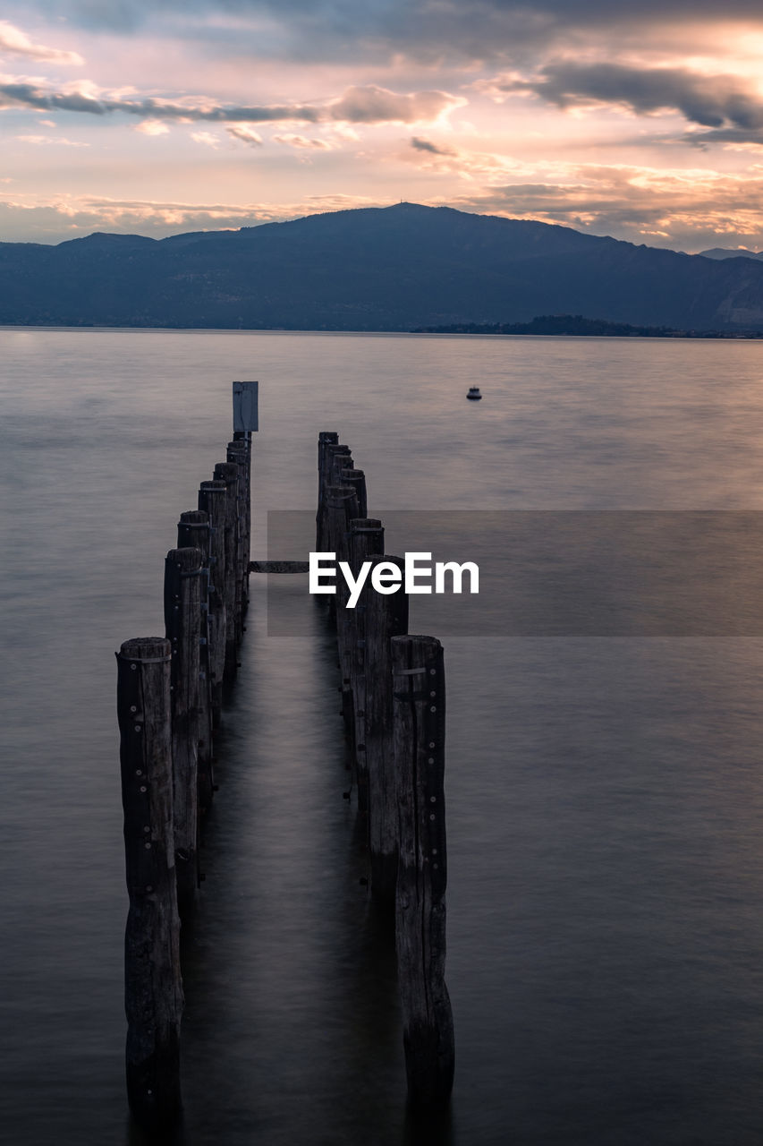 water, horizon, reflection, sky, sea, cloud, dawn, scenics - nature, sunrise, beauty in nature, nature, tranquility, ocean, morning, tranquil scene, wood, pier, coast, landscape, no people, environment, outdoors, land, dramatic sky, bay, travel destinations, seascape, idyllic, beach, architecture, mountain, wooden post, shore, post, travel, body of water, sunlight, non-urban scene, jetty