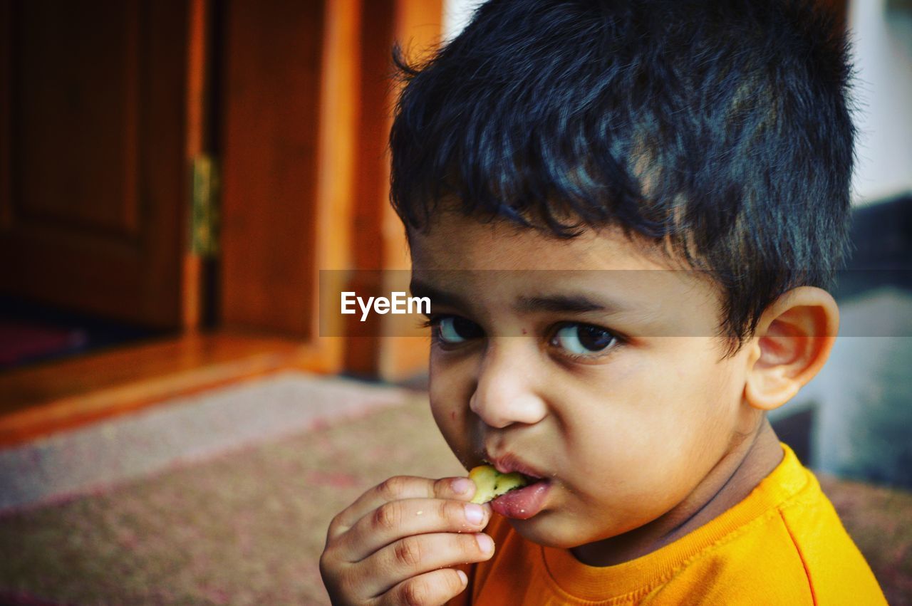 Close-up portrait of boy having food at home