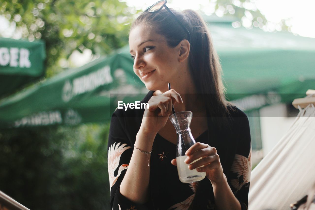 Smiling woman having drink outdoors