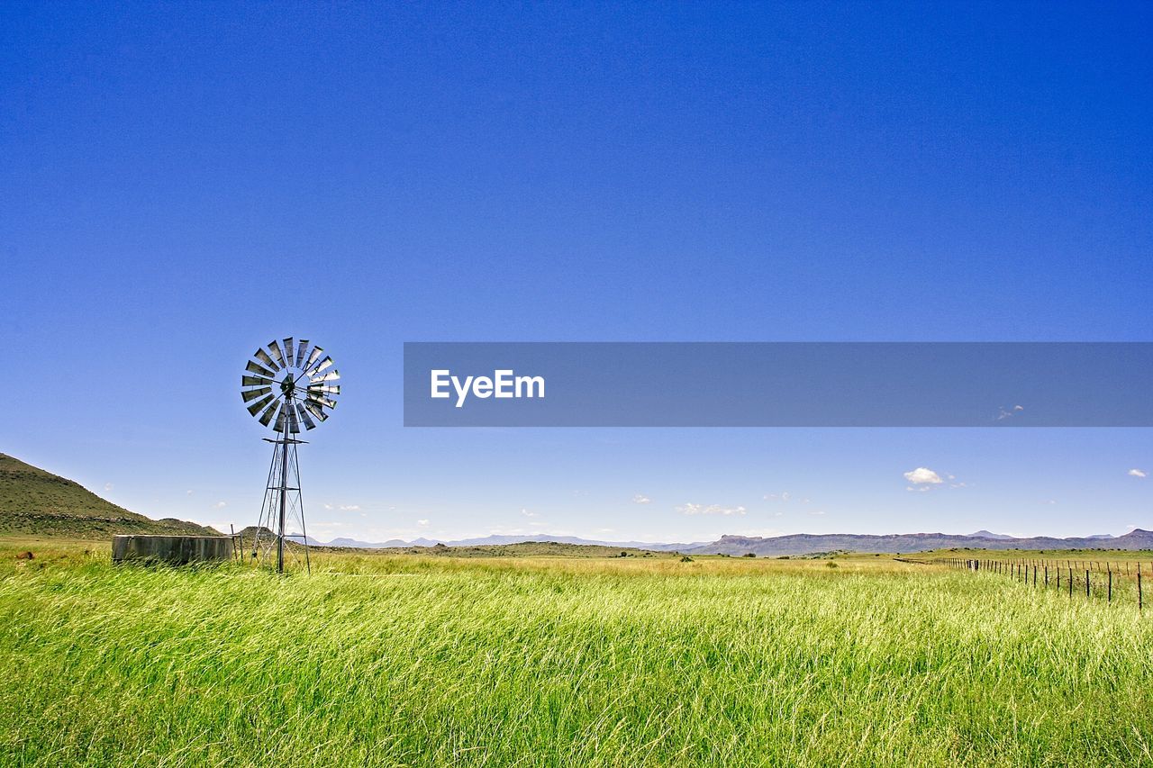 WINDMILL ON FIELD AGAINST BLUE SKY