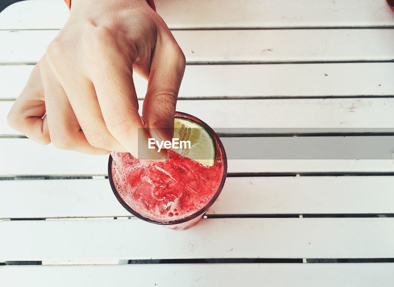Cropped image of person hand with drink served on table