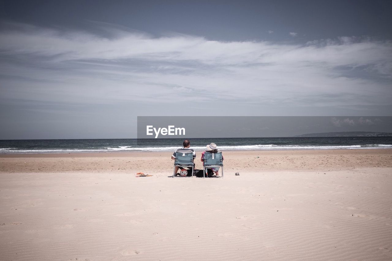 Rear view of couple overlooking calm sea