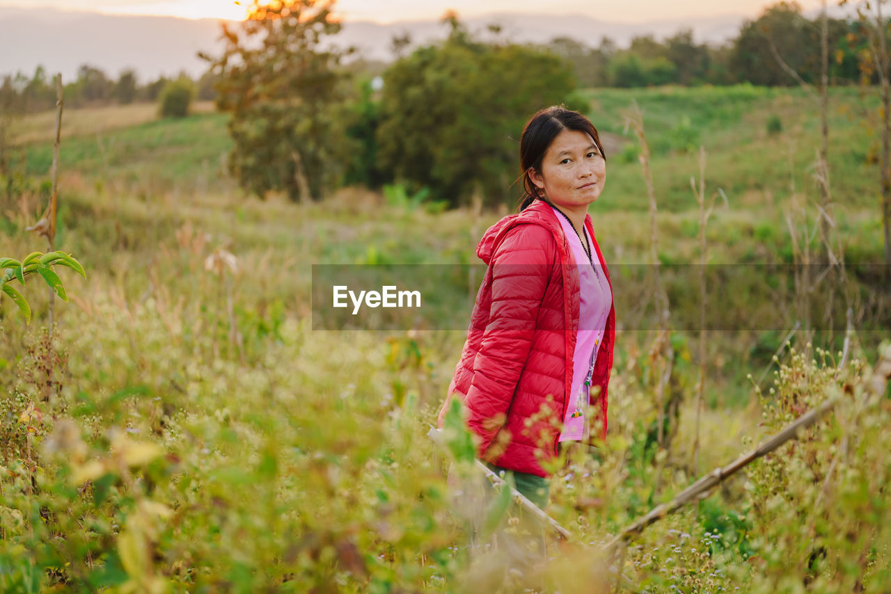 portrait of young woman standing amidst plants on field