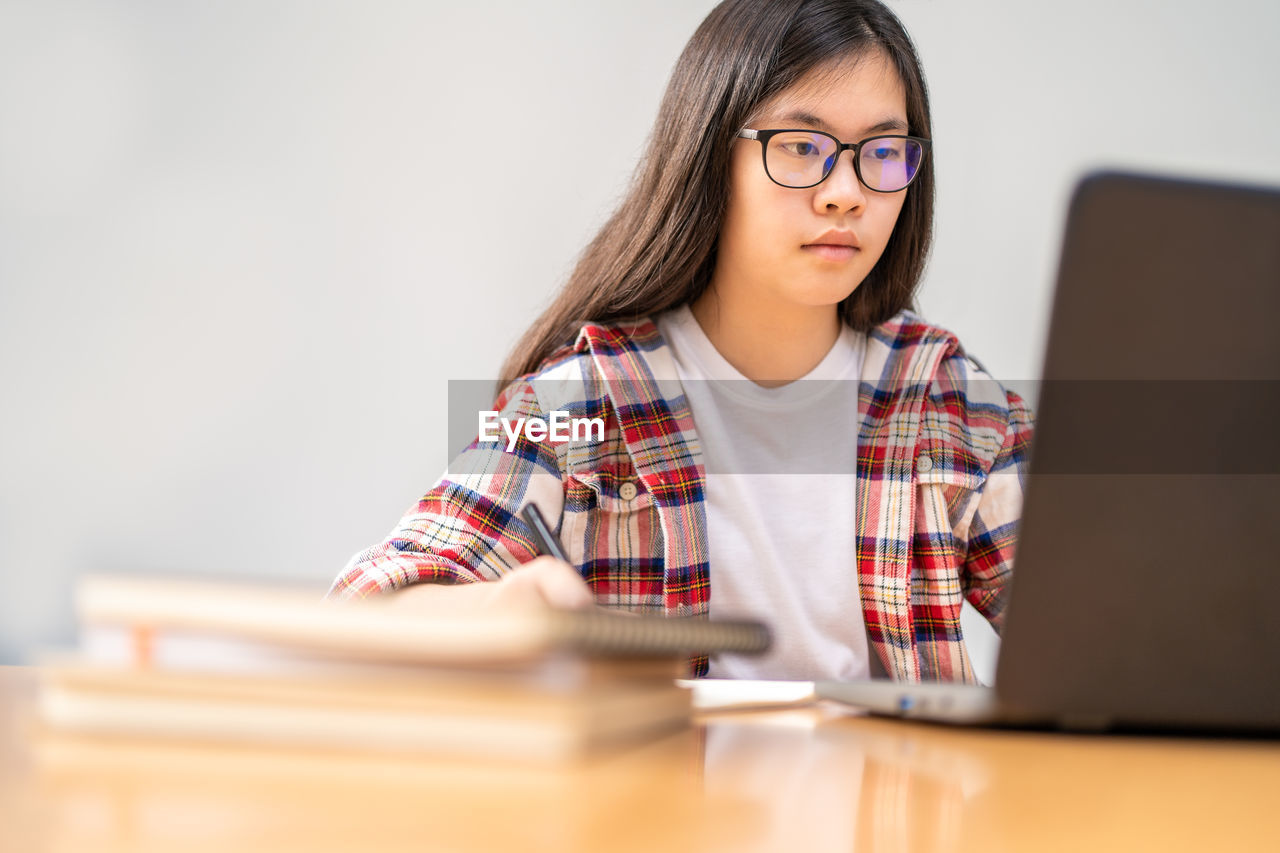 Young asian female student working and studying from home during the city lockdown due to covid-19