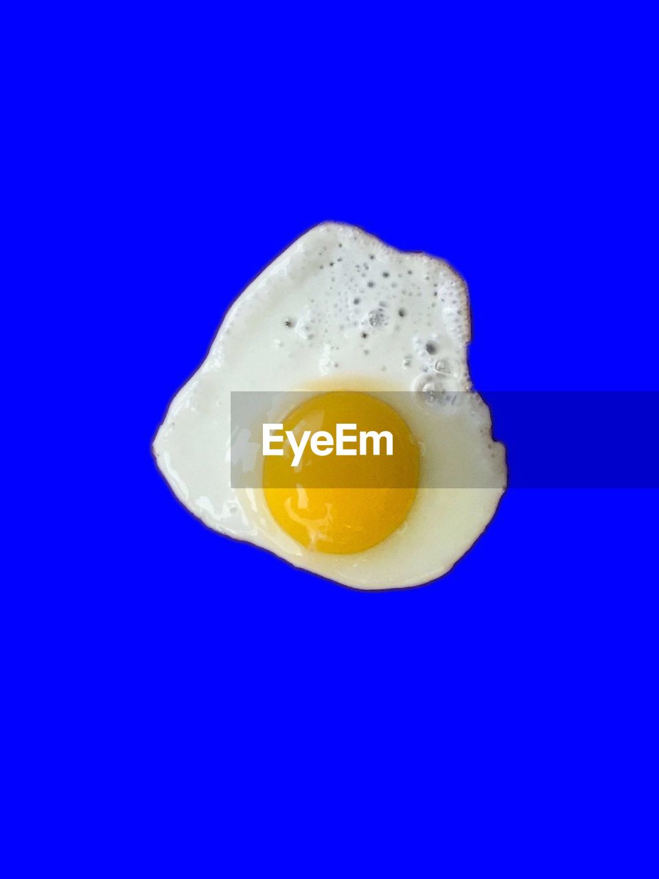 CLOSE-UP OF YELLOW EGG OVER BLUE BACKGROUND