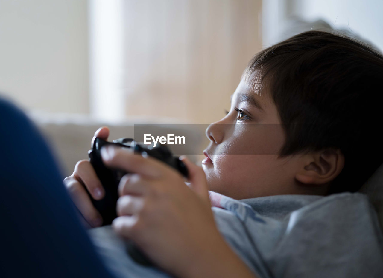 Portrait of boy holding camera at home