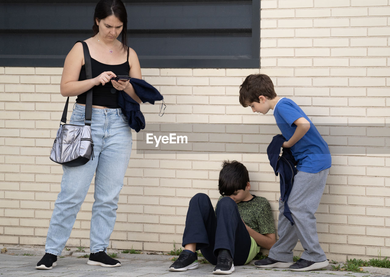 Family of mother and two kids addicted and obsessed with modern gadgets in the street