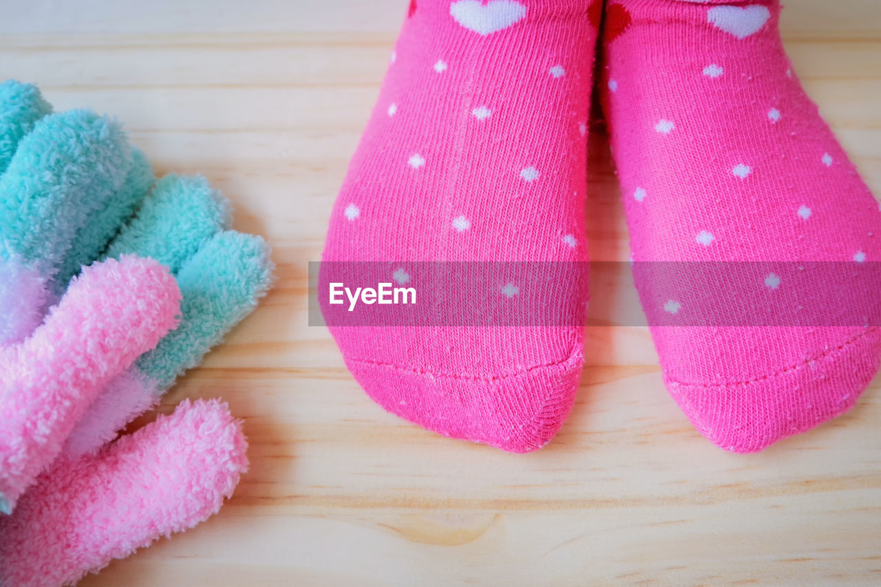 Low section of woman wearing pink socks on hardwood floor