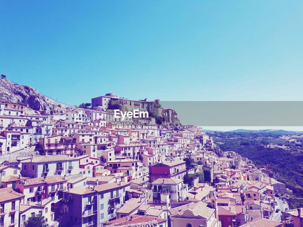 Houses in town against clear blue sky