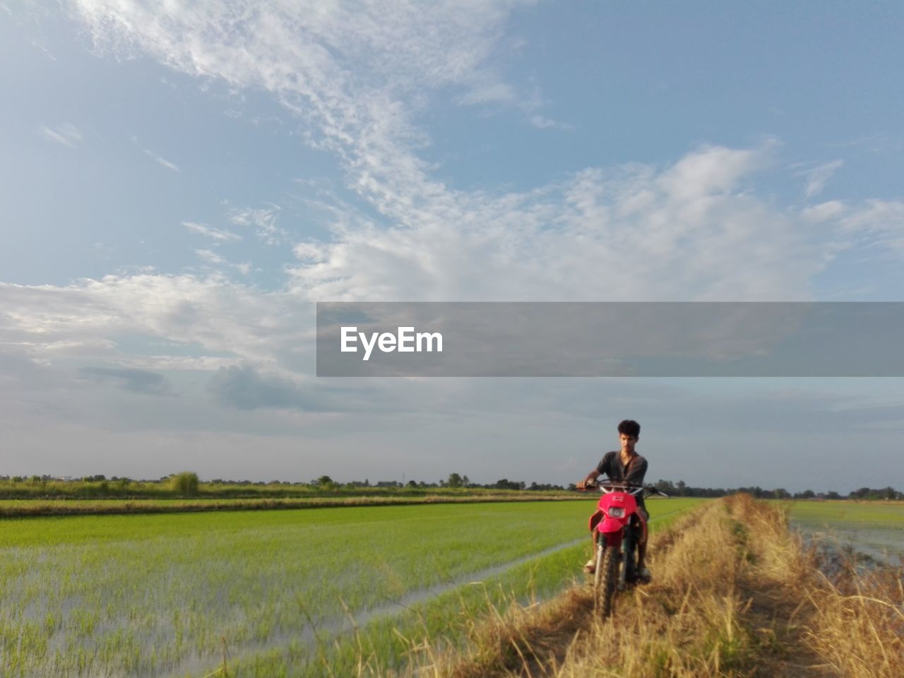 sky, landscape, prairie, rural area, field, grassland, environment, rural scene, agriculture, nature, land, cloud, adult, plant, one person, horizon, plain, meadow, grass, transportation, beauty in nature, steppe, day, motion, hill, women, full length, crop, scenics - nature, copy space, bicycle, cereal plant, natural environment, outdoors, activity, lifestyles, farm, leisure activity, travel, on the move, walking, rear view, cycling, tranquility, non-urban scene, road, sports, mature adult, men, vehicle, sunlight, growth, riding, paddy field, female