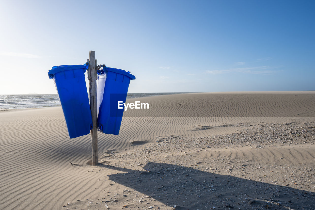 Blue bins on the beach under a sunny sky