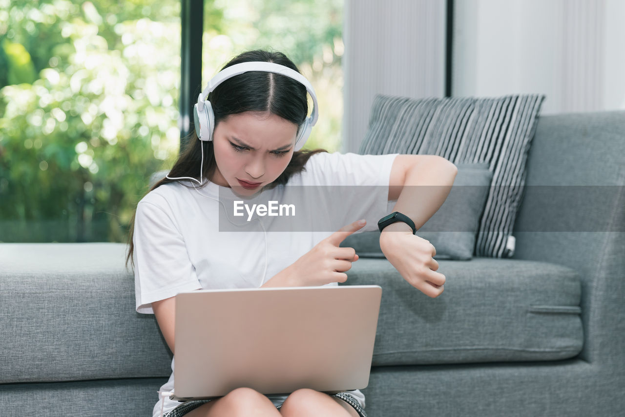 MAN USING SMART PHONE WHILE SITTING ON SOFA