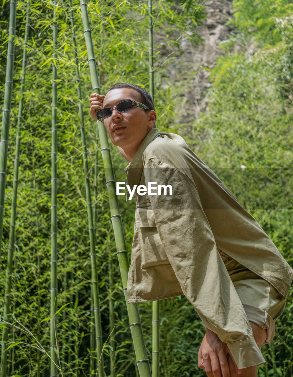 PORTRAIT OF MAN WEARING SUNGLASSES STANDING ON PLANTS