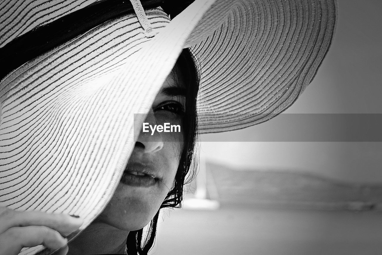 Close-up of young woman covering face with hat