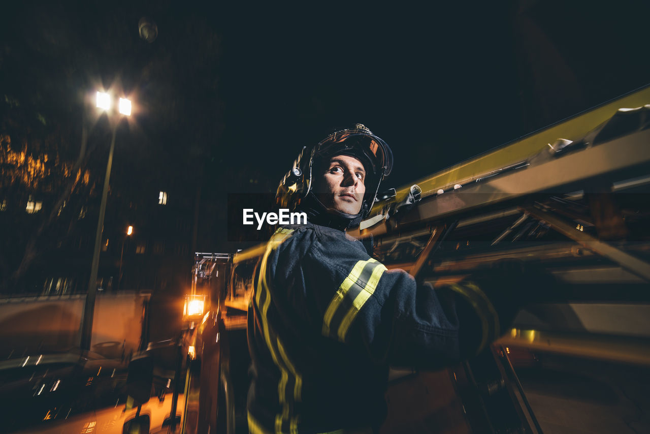 Firefighter riding on outside of fire truck at night