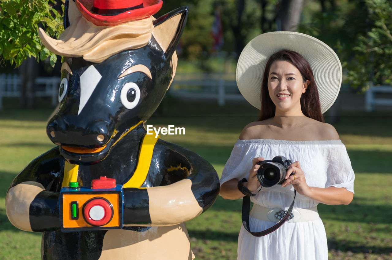 PORTRAIT OF WOMAN HOLDING CAMERA