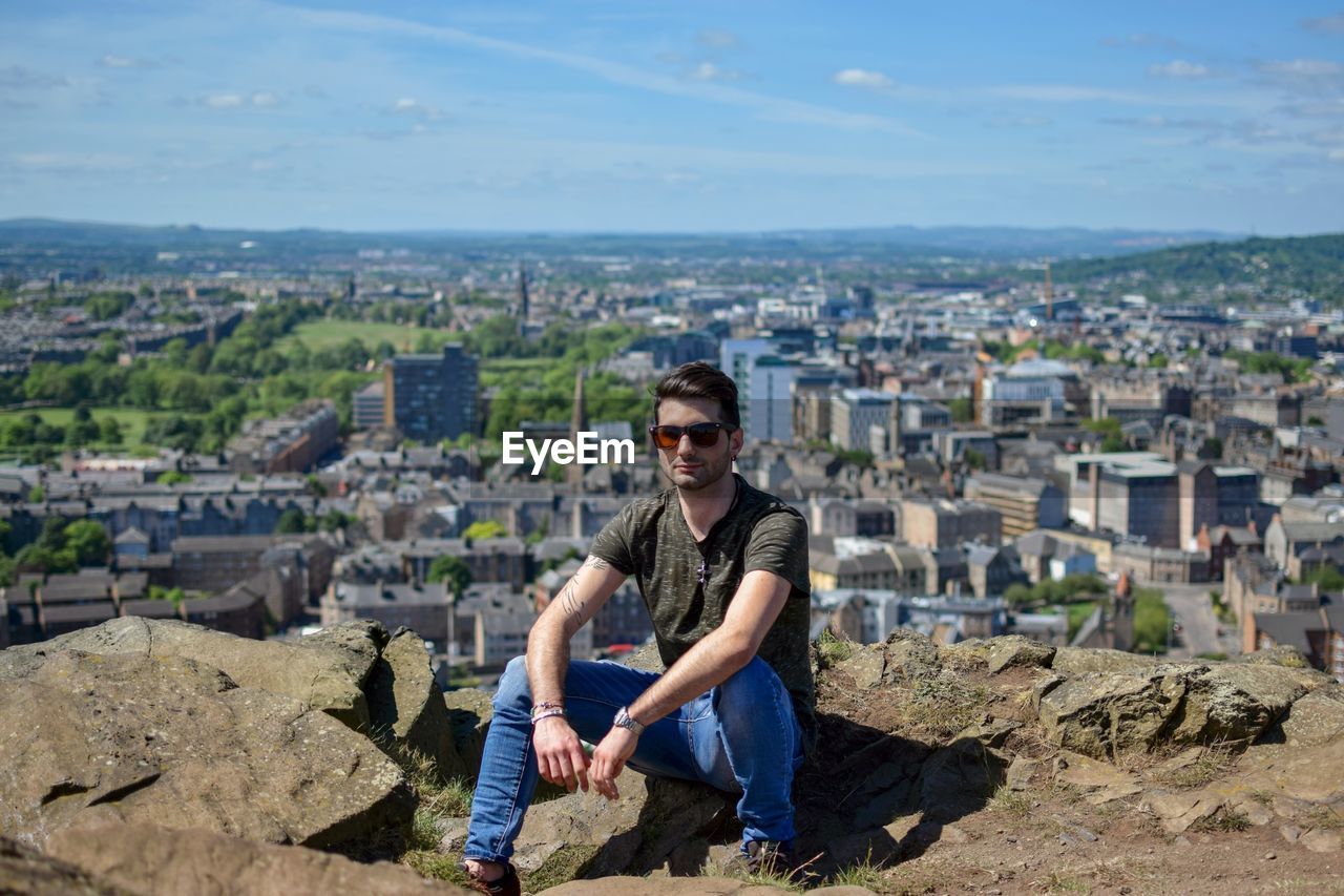 Full length of young man sitting on rock at holyrood park